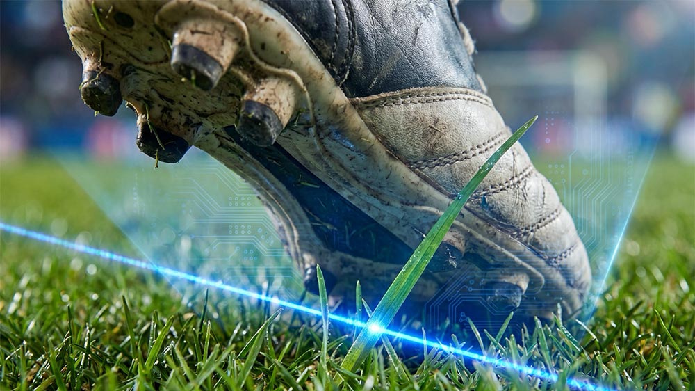 Soccer player's cleat near a digital offside line projected across the field.